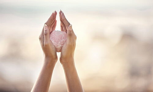 Frauenhände mit einem rosafarbenen Edelstein