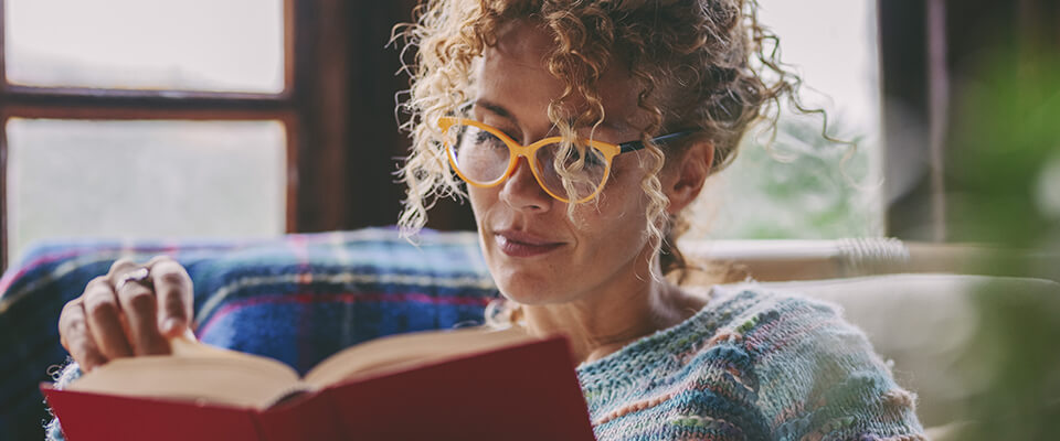 Frau mit Brille liest ein Buch aus dem Buchshop