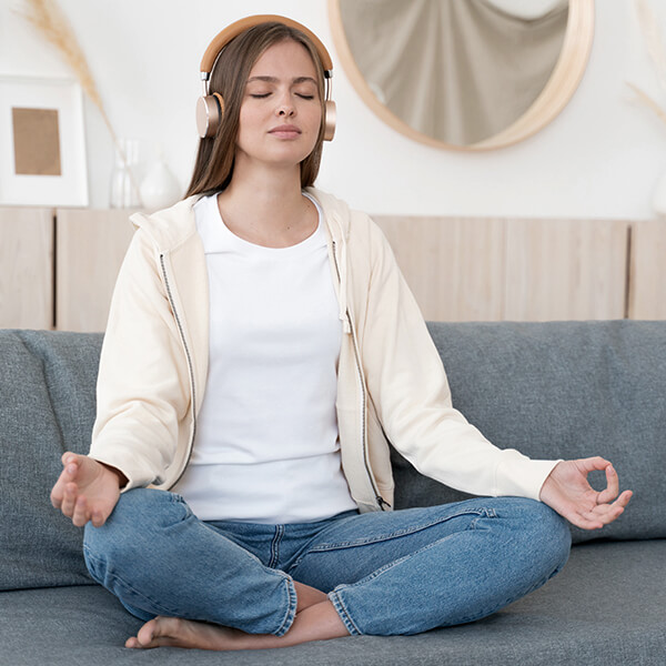 Junge Frau meditiert auf einem Sofa