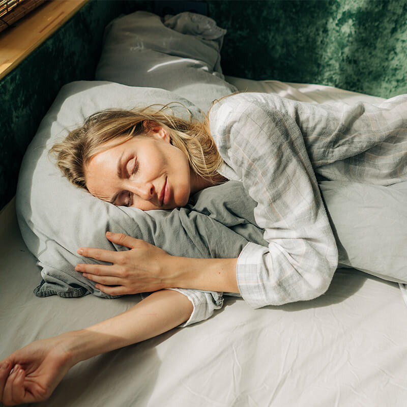 Blonde Frau schläft entspannt in ihrem Bett.