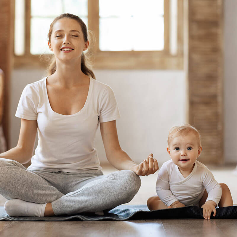Mutter mit sitzendem Baby beim Yoga